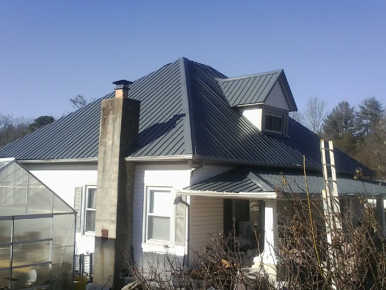 Dark blue standing seam metal roof on a white farmhouse with dormer — Slate & Tile Roof Repair by Roofing Brothers in Equinunk