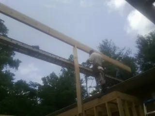 Carpenter setting a ridge beam over a new addition frame — Ice Dam Removal by Roofing Brothers in Equinunk