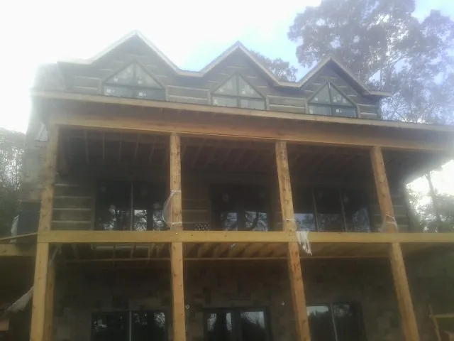 Dormers and porch framing on a large log home under construction — Roof Coating work by our crew in Equinunk