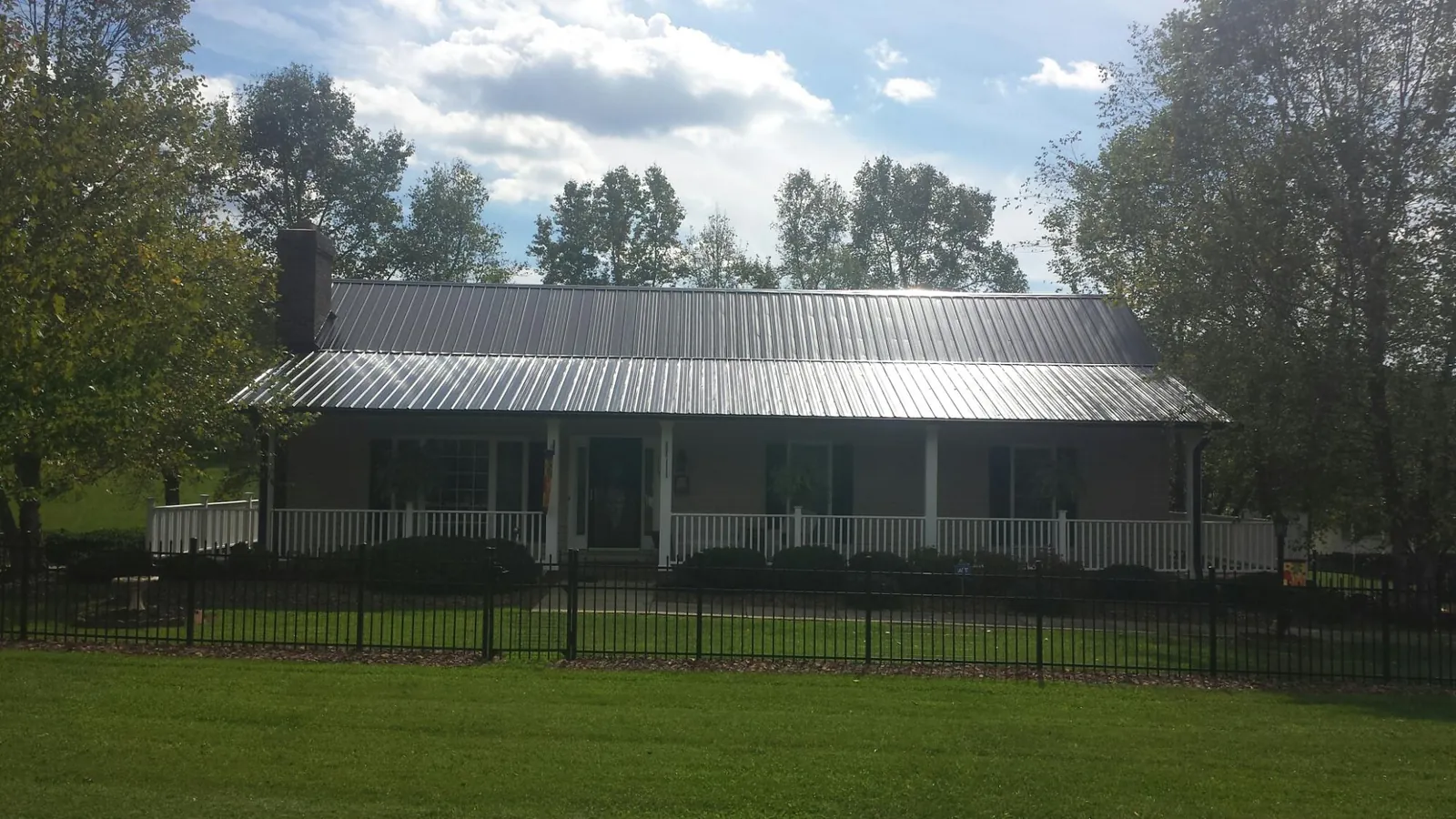 Gray metal roof on a brick ranch with a full width front porch — Gutter Guard Installation work by our crew in Equinunk