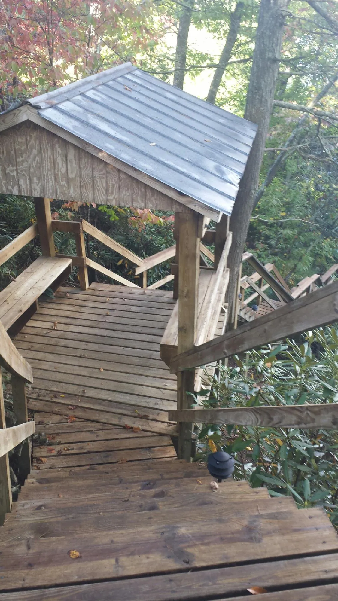 Metal roofed shelter over wooden steps on a wooded walkway — Skylight Repair & Installation work by our crew in Equinunk