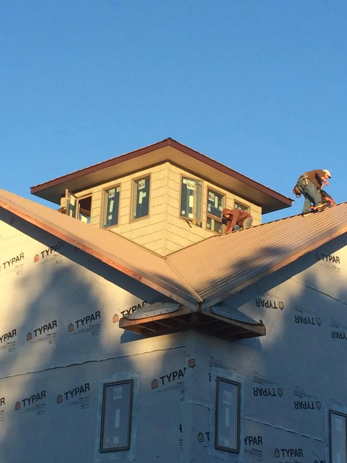Roofers working around a rooftop cupola on a new metal roof at sunset — Roof Waterproofing in Equinunk by Roofing Brothers